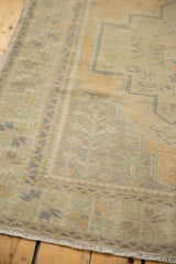 Distressed Oushak runner detail: muted sand, sea foam green geometric patterns and visible wear.