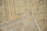 Folded Oushak rug with distressed pile, geometric patterns, and visible woven reverse.
