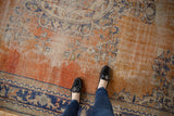 Distressed Oushak carpet texture showing worn pile, faded brick red, navy, and ivory patterns.
