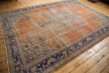 Vintage Oushak carpet with distressed brick red field, abrashes, and navy blue curvilinear motifs.