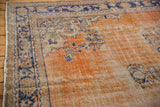 Distressed texture, faded brick red field, and navy vinery of a vintage Oushak rug.