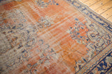 Distressed Oushak rug showing faded brick red field, navy, and ivory vinery pattern.