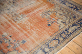 Distressed vintage Oushak rug corner featuring faded brick red, navy border, and ivory Rococo vinery.