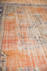 Distressed Oushak carpet with worn pile, showing faded brick red and navy blue Rococo vinery.