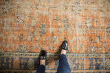Distressed apricot field showing worn floral blossoms, dusty teal accents, and part of a royal blue border.