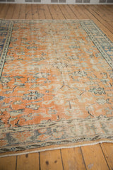 Distressed vintage Oushak carpet, worn apricot field with faded floral and vinery motifs.