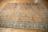 Distressed apricot field with scrolling vinery meets dusty teal palmette border on vintage Oushak.