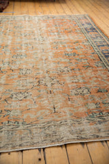 Apricot and antique ivory distressed Oushak texture, with faded floral vinery and blue border.