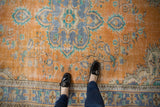 Faded terra cotta orange vintage Oushak rug with blue motifs and evident pile wear.