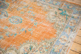 Distressed Oushak rug, faded orange field, blue floral patterns, and visible foundation.