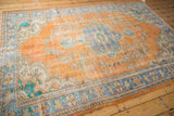 Distressed Oushak carpet with faded terra cotta orange and turquoise floral patterns and exposed foundation.