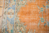 Textural detail of distressed vintage Oushak rug in faded tangerine orange and turquoise.
