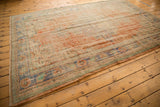 Secured side of vintage Oushak rug, with worn pile, apricot, mint, and pale blue colors.
