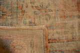 Distressed Oushak rug corner, showing mostly even wear to pile, secured edge, and woven back.