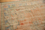 Distressed vintage Oushak rug corner, showing worn texture, apricot, mint, and blue border.