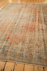 Corner of distressed Oushak rug with mostly even wear, mint green, sky blue, and apricot.