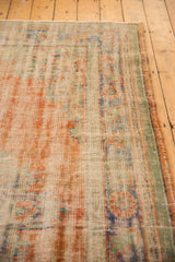 Distressed Oushak rug surface with apricot, mint, blue, ivory tones, mostly even wear, and secured side.