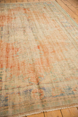 Distressed vintage Turkish Oushak rug corner, showing worn pile, visible foundation, and soft colors.