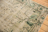 Distressed corner of vintage Oushak carpet, showing faded pale seafoam floral and tendril motifs.