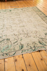 Distressed Oushak rug texture with faded mint green and charcoal allover floral tendrils.