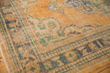 Textured border detail of a distressed Oushak rug in apricot, teal, and ivory.