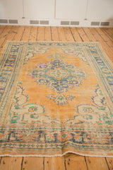 Decorative texture of a vintage distressed Oushak rug with worn apricot, mint, and teal colors.
