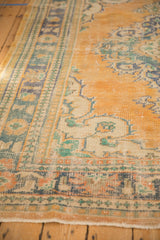 Worn pile and visible foundation on a distressed Oushak border with teal and apricot patterns.