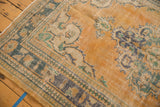 Corner of distressed Oushak rug, showing pale apricot field, dusty teal border, and visible foundation.