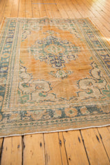 Distressed vintage Oushak rug corner: apricot peach field, dusty teal border, wear to knot heads.