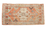 Distressed Oushak runner rug with faded brick red field and sea foam green floral medallion.