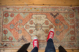 Distressed vintage Oushak rug runner with faded blush and sea foam green floral patterns.