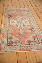 Distressed vintage Oushak runner detail showing blush red, sea foam green floral motifs.