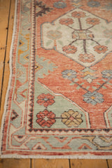 Distressed vintage Oushak rug displaying worn texture, pale red, and sea foam green floral patterns.