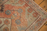 Corner of vintage distressed Oushak rug, displaying soft floral motifs and faded brick red, sea foam green palette.
