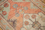 Distressed Oushak rug with worn pile texture in pale blush brick and sea foam green florals.