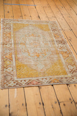 Corner detail of distressed Oushak rug, faded saffron and ivory with meandering vine and seed motifs.