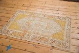 Distressed Oushak rug corner with faded gold, ivory, and pale bronze botanical motifs.