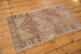 Vintage distressed Oushak rug corner showing worn pile, visible foundation, and muted pink, beige, brown motifs.