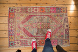 Vintage distressed Oushak rug with geometric medallion, vibrant faded purple, orange, and blue tones.