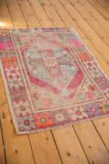 Distressed lower right corner of a vintage Oushak rug, showing geometric motifs, worn pile, and secured fringe.