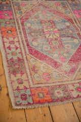 Distressed Oushak rug corner showing playful pink, orange, and blue tones with visible knot heads.