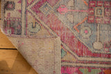 Distressed vintage Oushak rug corner with worn, colorful geometric pile and visible woven foundation.