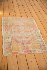 Distressed texture and secured fringe of the Oushak rug, showing pink and pale gold.