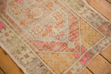 Distressed vintage Oushak rug corner with vibrant pink, pale gold, and rust colors.