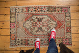 Distressed vintage Oushak rug detail showing stepped diamond medallion and worn rust, beige pile.