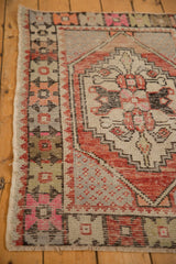 Detail of vintage distressed Oushak rug corner showing serrated rust pattern, pink buds, and wear.