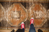 Distressed Oushak runner with faded rust terra cotta and charcoal geometric patterns.