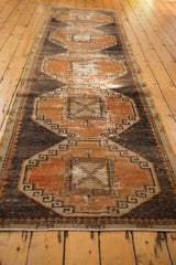 Distressed Oushak runner's geometric medallion, rust terra cotta and charcoal, featuring ivory wear.