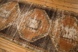 Distressed Oushak runner's geometric medallion in rust, charcoal, ivory, with visible hard wear.