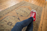 Distressed vintage Oushak runner with soft apricot, beige, seafoam field, and medallion pattern.